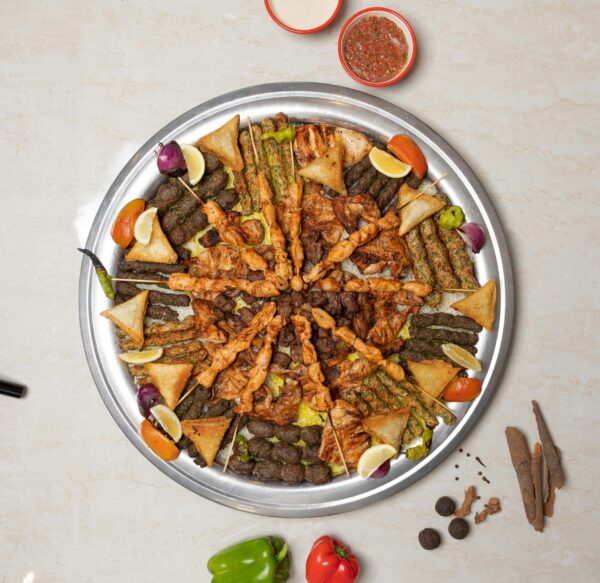 Delicious Middle Eastern kebab platter with various meats and fresh vegetables, top view.