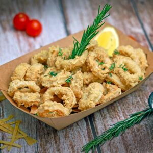 Delicious crispy fried calamari served with lemon and dipping sauce on wooden table.