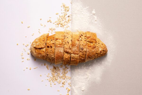 Freshly sliced whole grain bread with oats and flour provides a rustic and nutritious appeal.