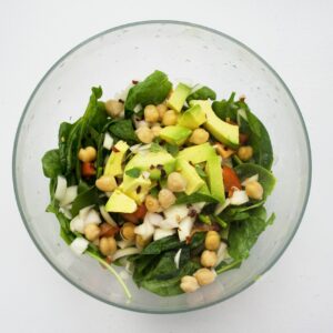 Fresh spinach salad featuring avocado and chickpeas, perfect for healthy eating.