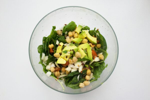 Fresh spinach salad featuring avocado and chickpeas, perfect for healthy eating.