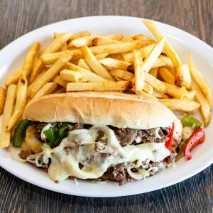 Mouth-watering Philly cheesesteak with melted cheese and french fries.