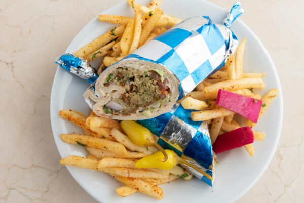 Delicious falafel shawarma wrap with crispy fries served on a plate in Santa Monica.