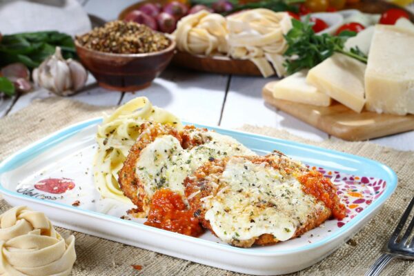 Tasty chicken parmesan with pasta and fresh ingredients on a rustic table.